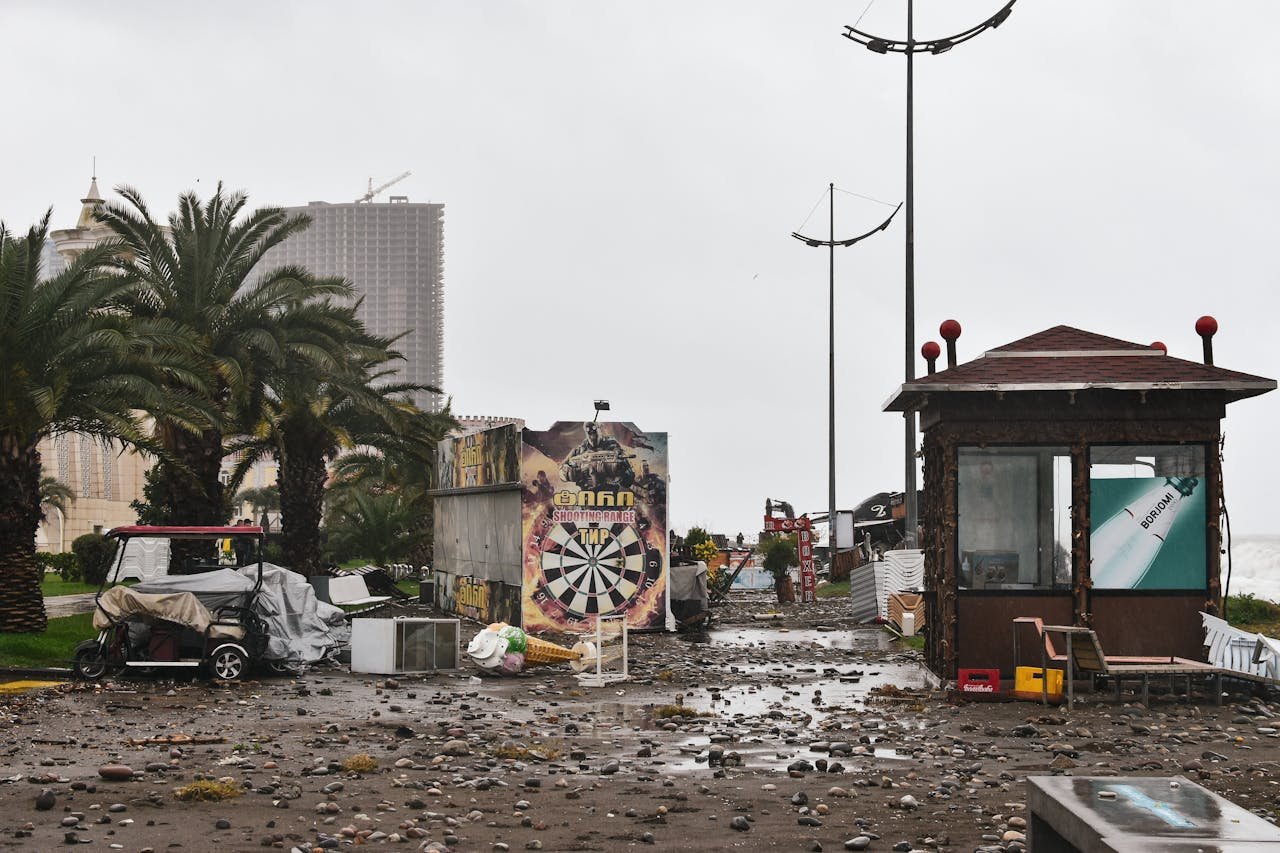 City street filled with storm debris and damaged structures under a cloudy sky.